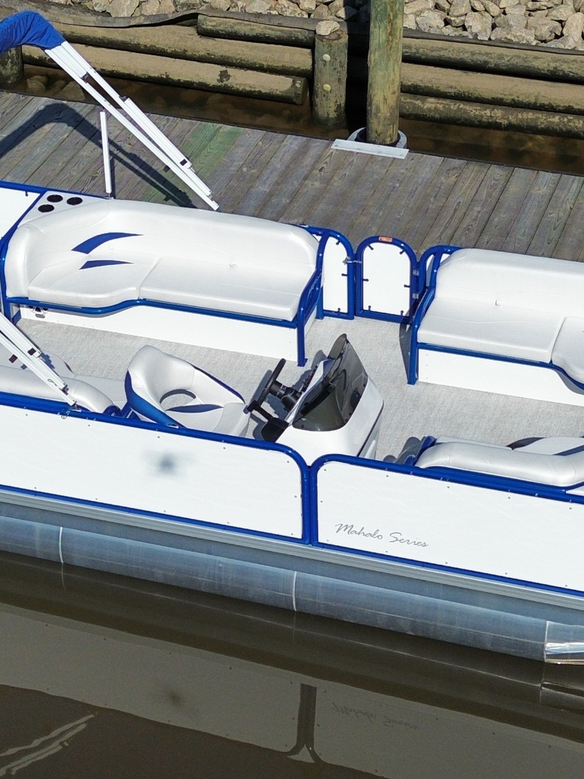 Pontoon boat docked with blue and white seating, viewed from above.